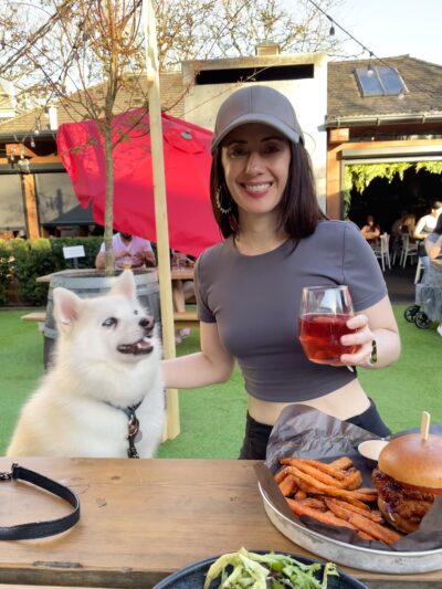 Michelle Shepherd RD – Patio with Loki and Fries Michelle Shepherd, Registered Dietitian in Langley BC, smiling on a patio with her dog Loki, a plate of sweet potato fries, and a glass of wine.